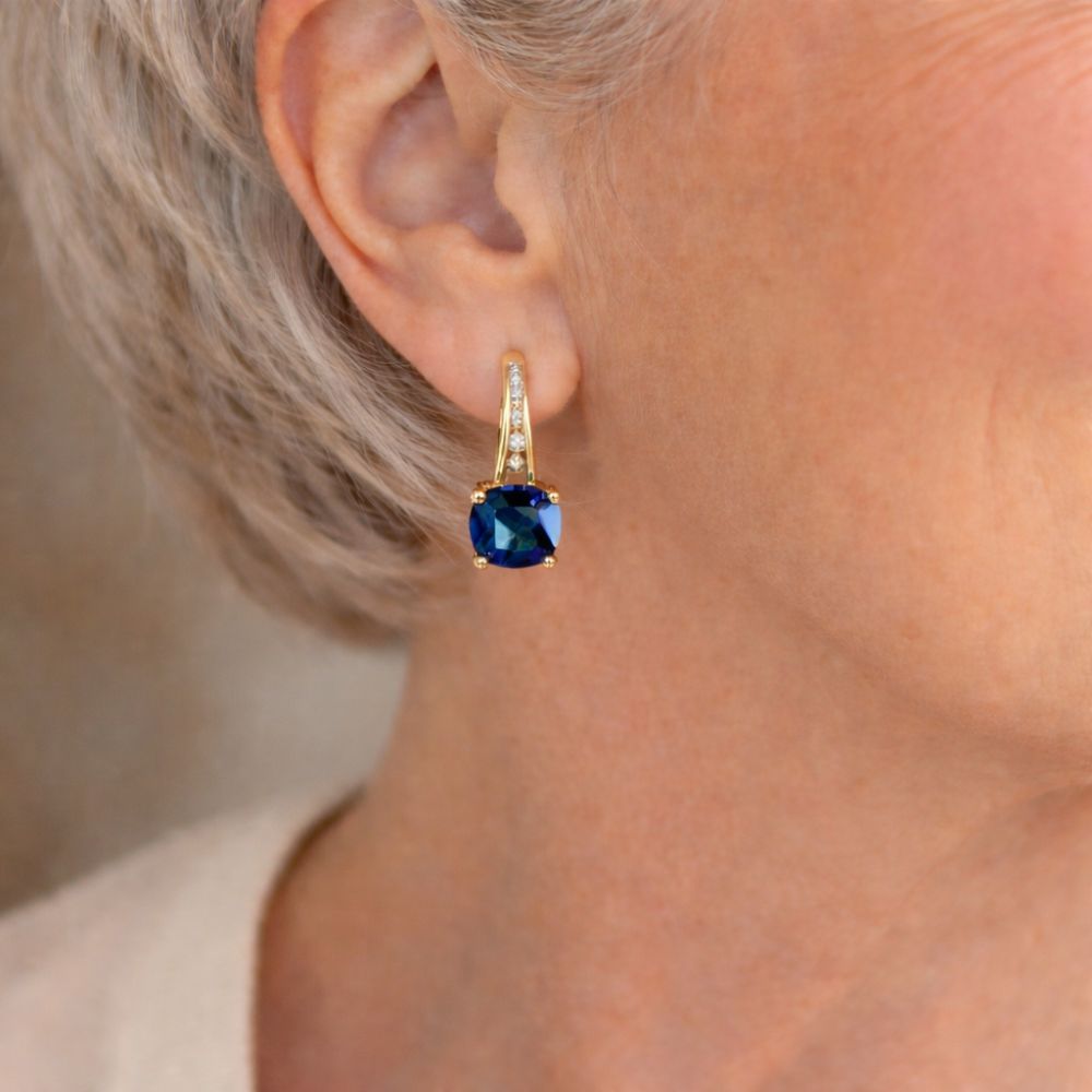 Aretes de argolla con piedra zafiro mística, hechos por Rose & Oliver, con detalle de piedras azules y acabado en metal brillante.