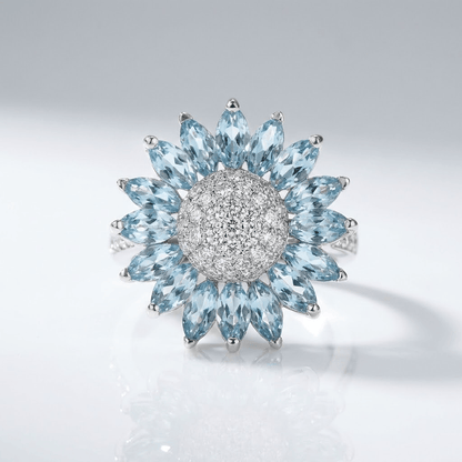 Silberner Ring mit blauem Topas in Blumenform, von der Marke Rose & Oliver, mit feinen Details und glänzenden Steinen.